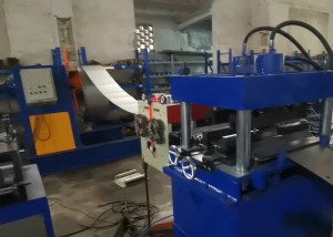 Imagen de una instalación industrial que muestra un desenrollador hidráulico con una gran bobina de acero, conectado a un mecanismo alimentador servo amarillo, preparando el acero para su posterior procesamiento.