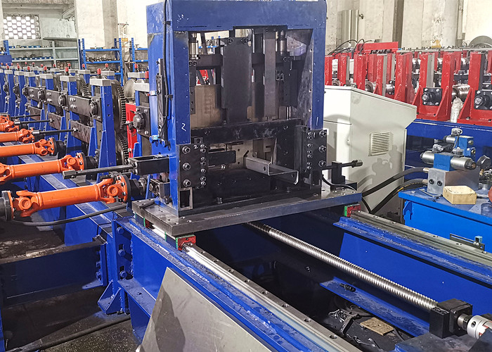 Primer plano de un dispositivo de corte volante multifuncional integrado en una máquina perfiladora, donde se observa metal moldeado pasando a través de él, listo para cortes de precisión.