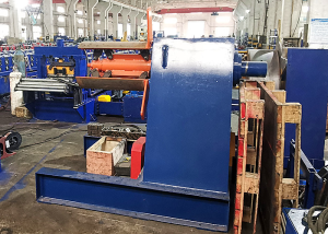 Un gran desenrollador hidráulico que sostiene una enorme bobina de acero galvanizado, ubicado en un espacioso taller industrial.