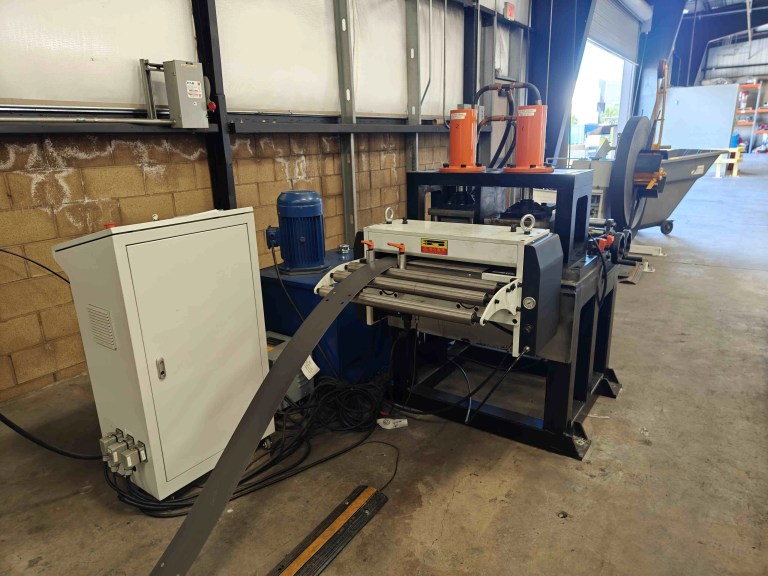 A close-up view of a servo feeder integrated with a punching device. The feeder mechanism precisely advances the material into the punch press where holes or slots are being stamped out.