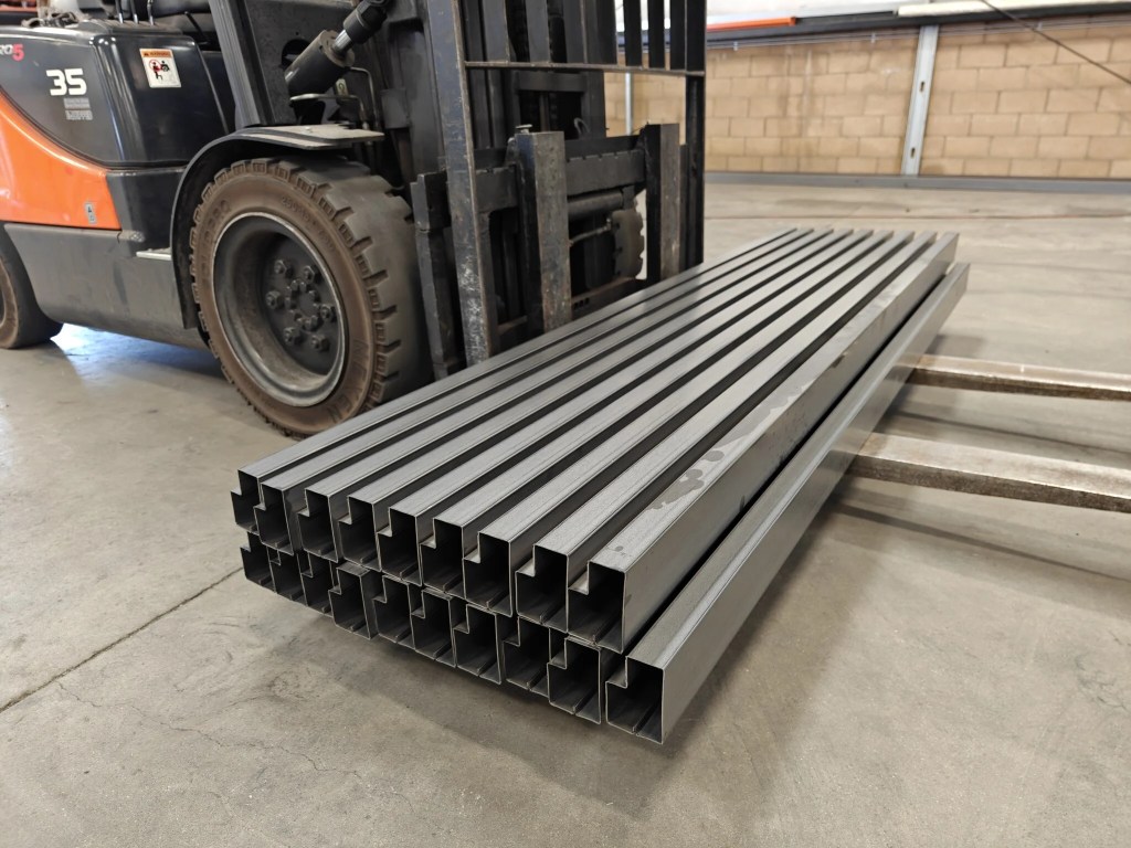 Amostra de perfil de viga escalonada acabada, utilizada em sistemas de estanteria para paletes de alta resistência.