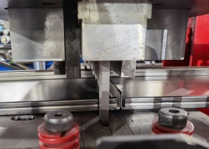 O potente mecanismo de corte hidráulico realiza um corte limpo e de alta velocidade em um poste de prateleira parcialmente formado.