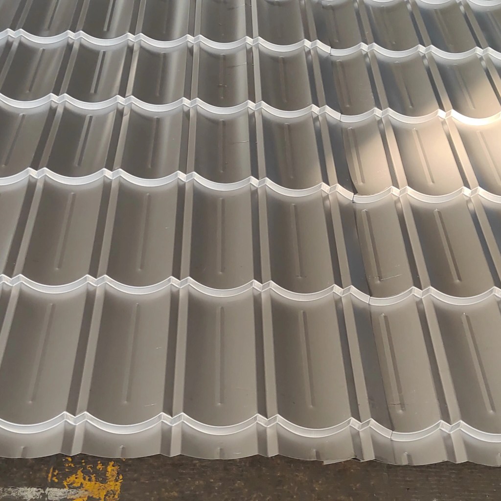 Close-up photo of a metal step tile roofing profile showing overlapping edges and deep steps.